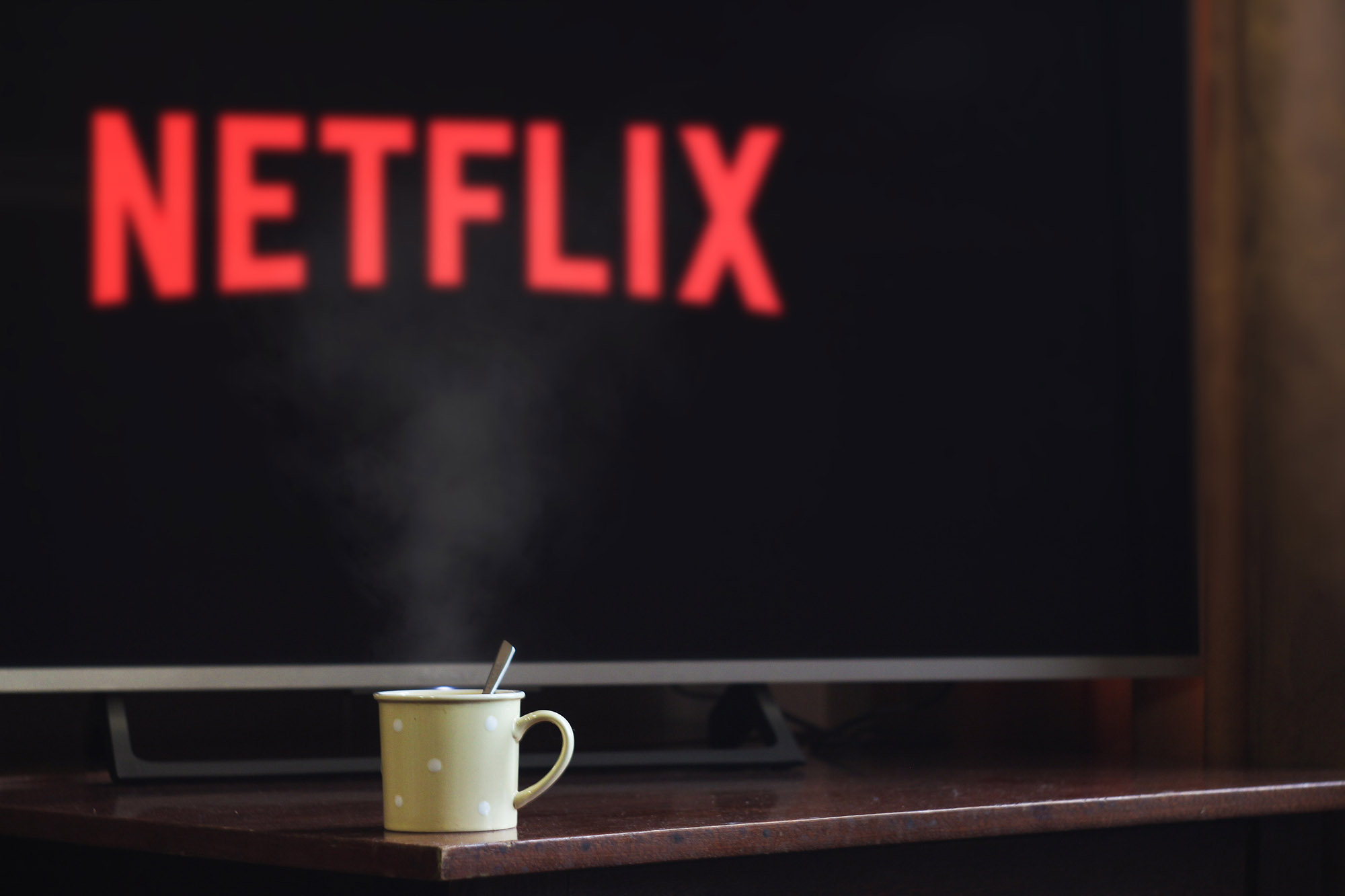 Photo of television showing Netflix logo behind a steaming beverage mug