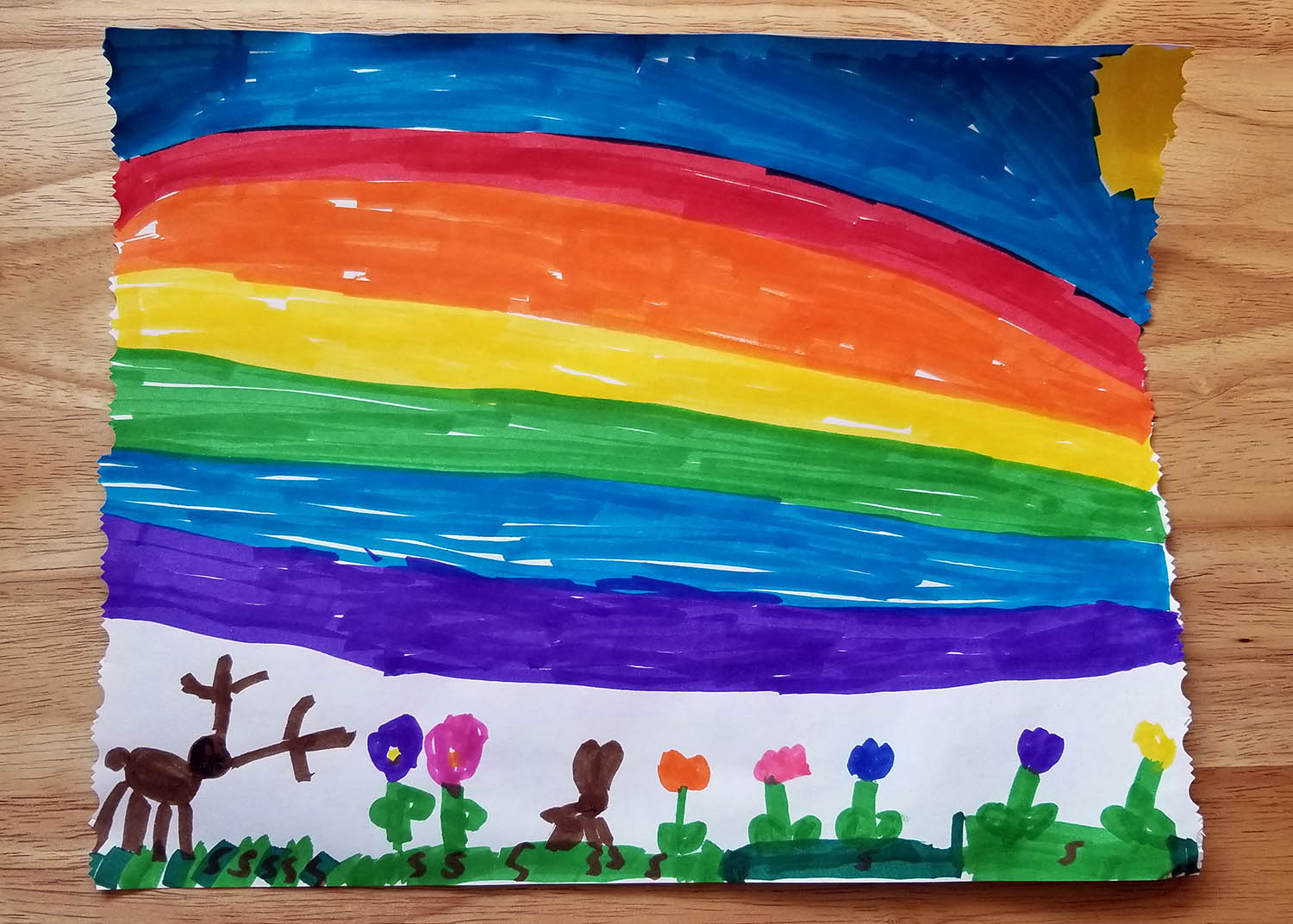 A child's drawing of a rainbow, flowers, and a deer