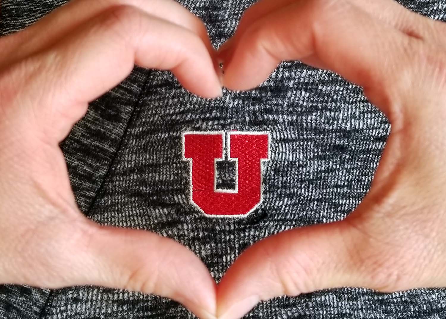 Two hands making a heart around the block U logo