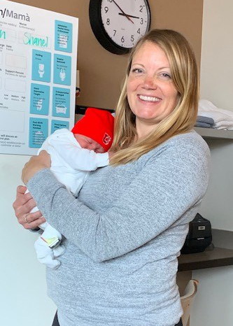 Dr. Alysse Loomis holding a very small baby with a red University of Utah hat