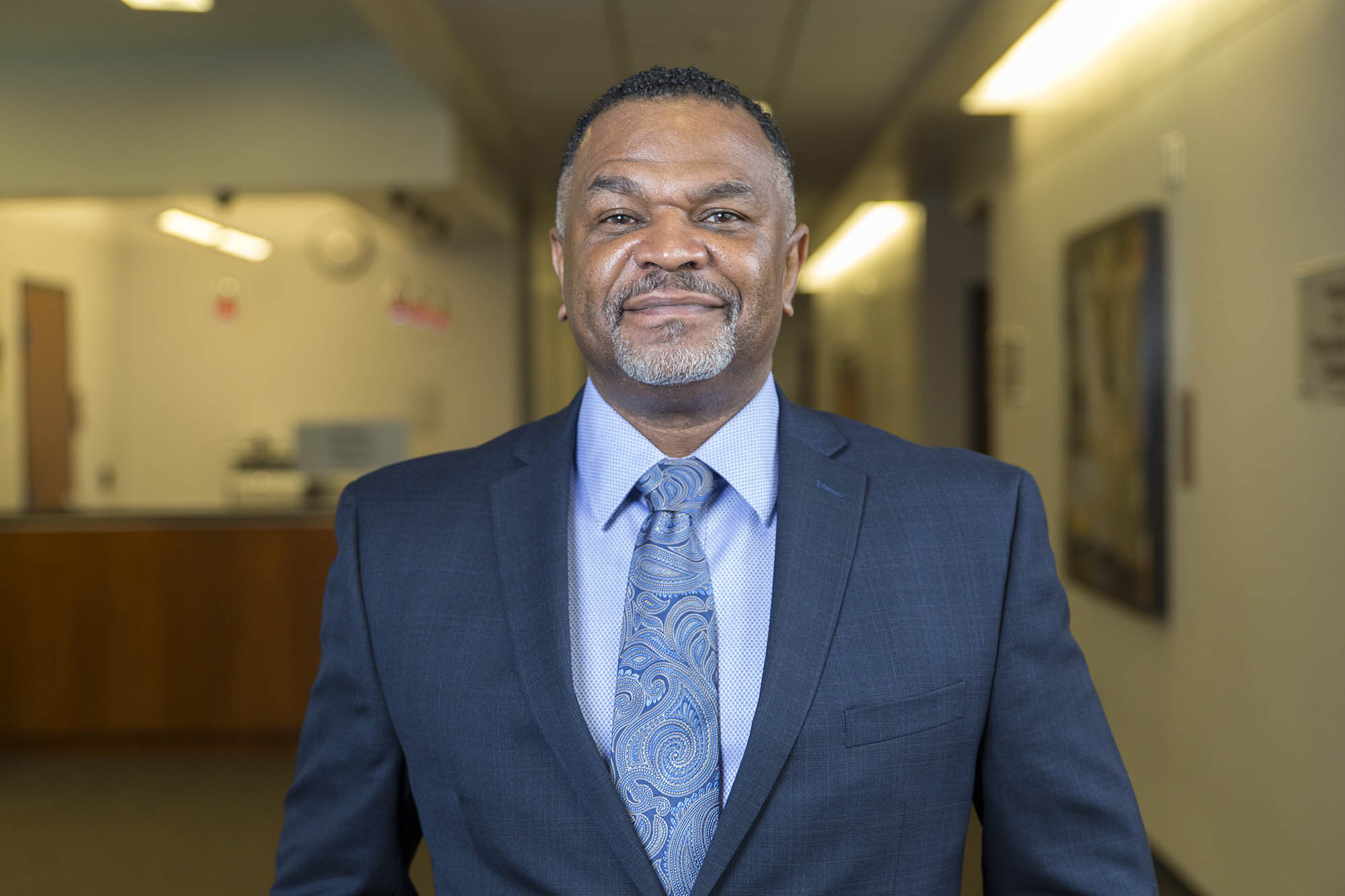 Dean Martell Teasley smiles at the camera while standing in the hallway of the Goodwill Humanitarian Building