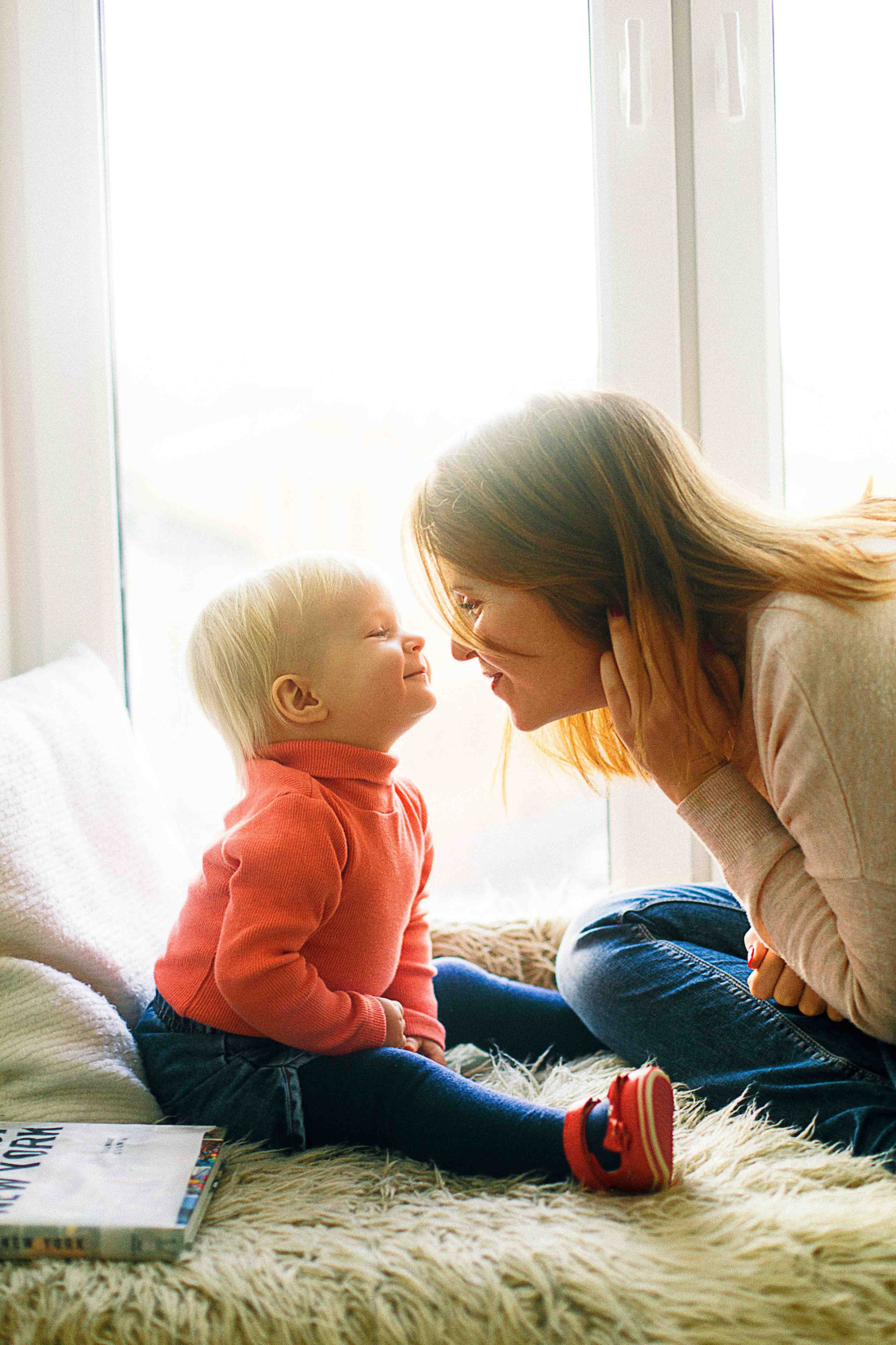 a toddler boy and a mother face each other and look into each other's faces.