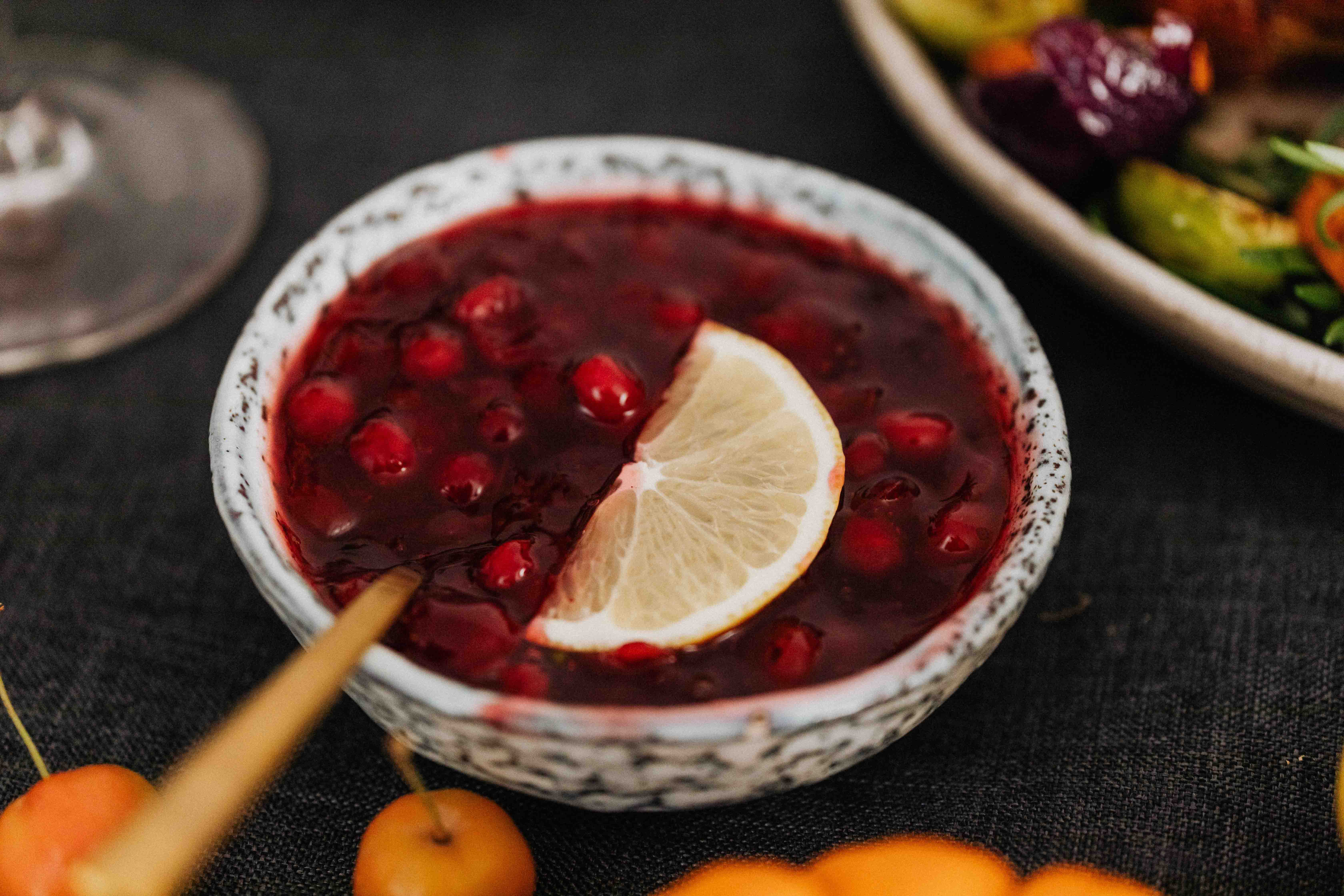 a bowl of cranberry sauce sits on table with festive decor surrounding it
