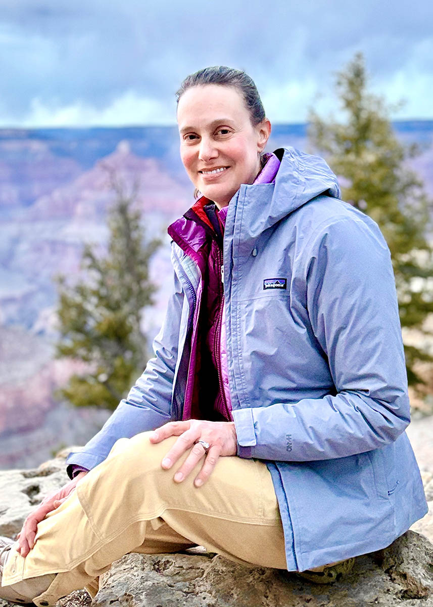 Dr. Joanna Bettmann smiles at the camera while sitting in front of the Grand Canyon
