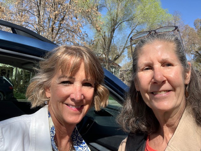 A selfie of two women smiling outside with the sun shining.