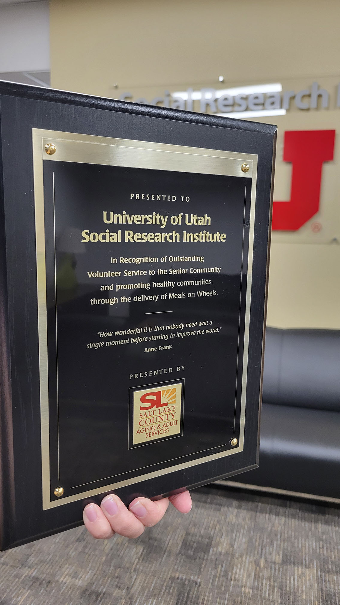 A hand holding a plaque displaying an award.